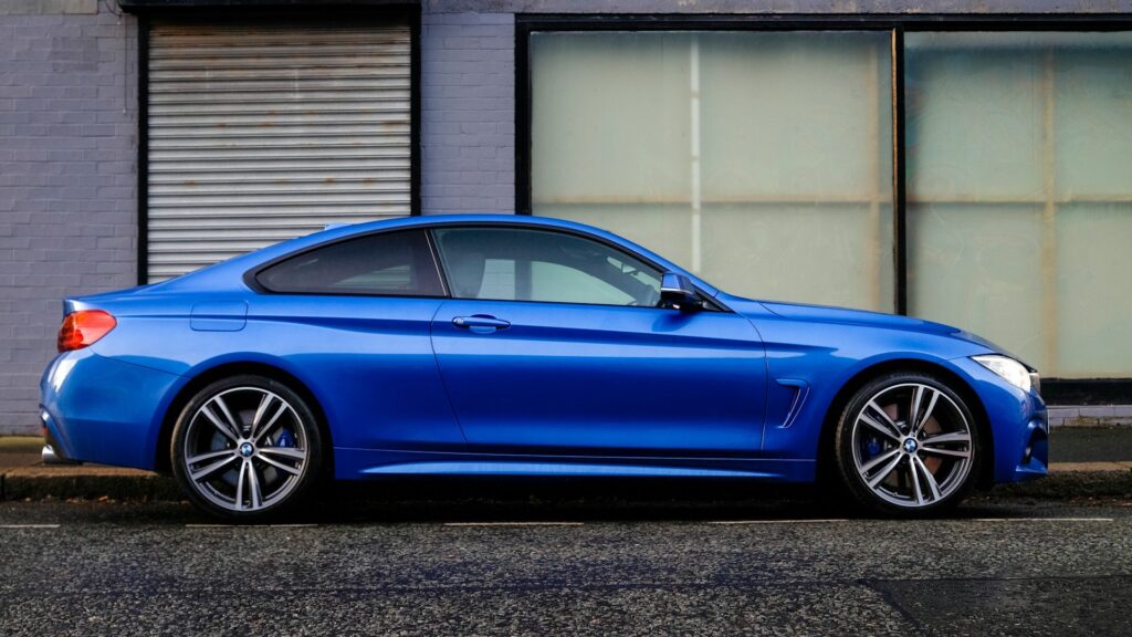 Blauwe coupé geparkeerd in stad, voorbeeld van correcte tenaamstelling van een auto