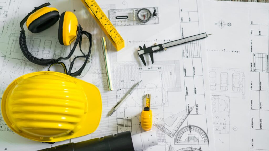 Bouwtekeningen met helm, meetgereedschap en bouwtools gebruikt bij voorbereiding voor vergunningsvrij bouwen