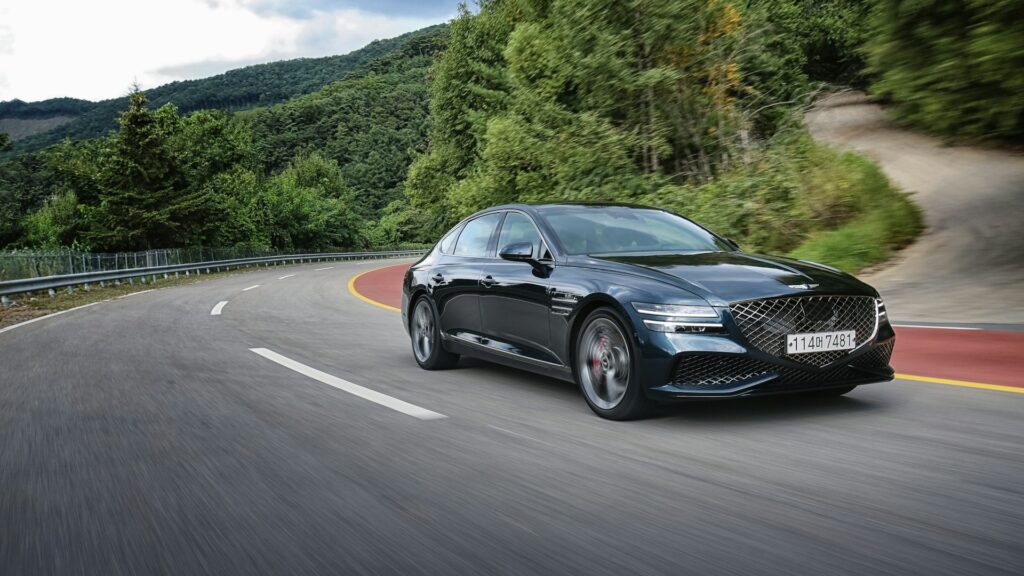 Zwarte sedan rijdt door bochtige bergweg tijdens tenaamstelling van een voertuig in praktijk