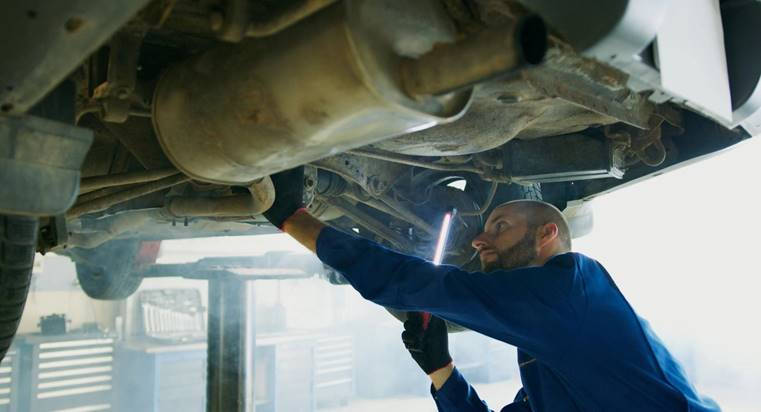 Monteur controleert het onderstel van een auto tijdens uitgebreid auto-onderhoud