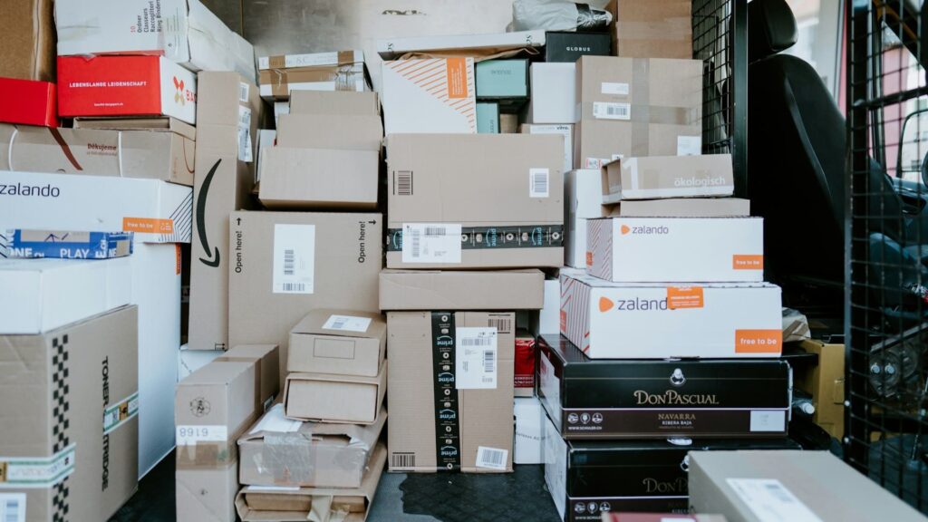 Stapel retourpakketten van kledingwinkels in een bezorgbus